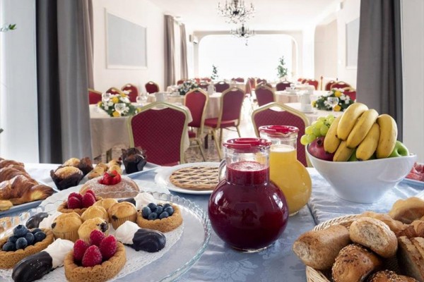 Slavnostně prostřený stůl s ovocem, džusy a dezerty v restauraci s červenými židlemi.
