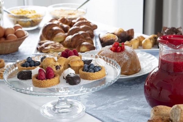 Stůl s různými dezerty včetně ovocných koláčků a tác s croissanty.