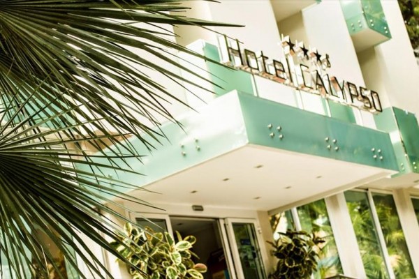 Vchod do hotelu Calypso se zeleným nápisem a čtyřmi hvězdami na fasádě.