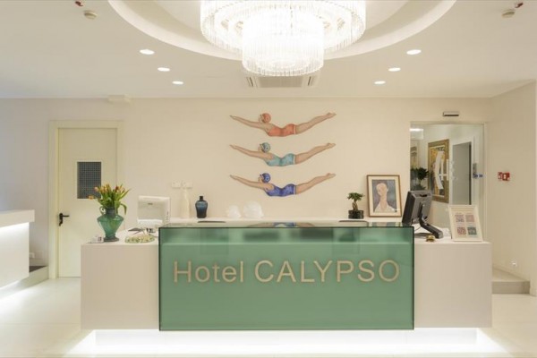 Recepce hotelu Calypso s moderním osvětlením a dekorací plavců na zdi.