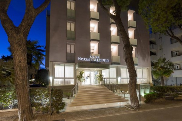 Vchod do hotelu Calypso večer s nasvícenými schody a stromy po stranách.
