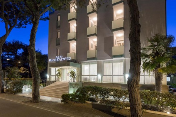 Fasáda osvětleného hotelu se schody a balkony večer.