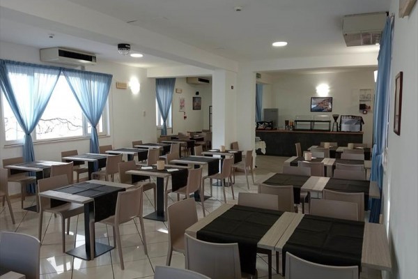 Restaurace s uspořádáním stolů a židlí, modré závěsy na oknech.