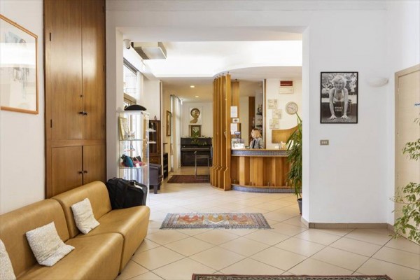 Recepce hotelu s dřevěným pultem a křeslem v popředí.  