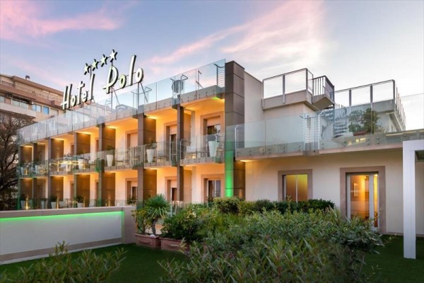 Moderní budova hotelu s prosklenými balkony a velkým nápisem Hotel Polo na střeše.