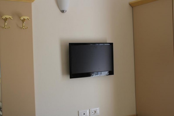 Televize pověšená na béžové zdi mezi skříňkami.