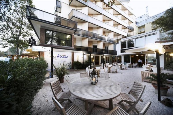 Moderní hotel s venkovní terasou a kulatými dřevěnými stoly.