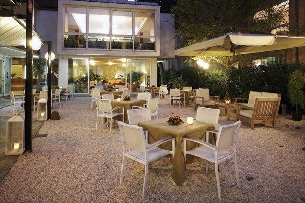 Venkovní terasa restaurace s osvětlením, stoly a židlemi.