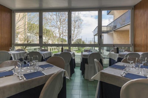 Restaurace s prostřenými stoly a velkými okny s výhledem do zahrady.