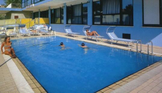 Venkovní bazén s několika lidmi, kteří relaxují a plavou.
