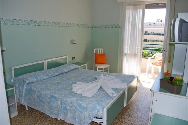 Pokoj s manželskou postelí a balkonem, na posteli svinuté ručníky.