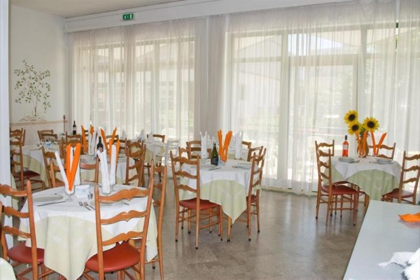 Restaurace s kulatými stoly ozdobenými ubrousky a slunečnicemi.