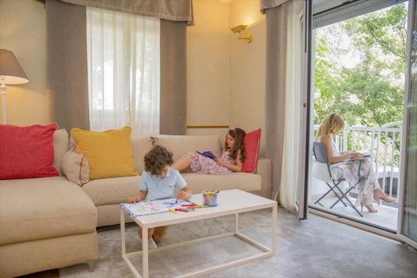 Tři děti relaxují a kreslí v obývacím pokoji a na balkóně.