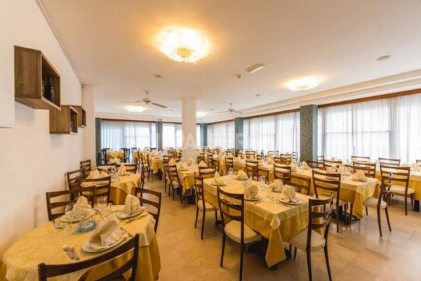 Restaurace se žlutými ubrusy a prostřenými stoly.