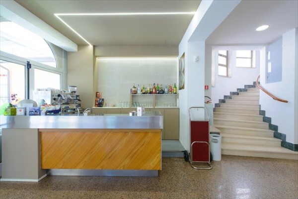 Bar s moderním designem a schodištěm v pozadí.