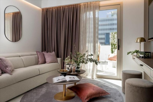 Moderní obývací pokoj s pohovkou, zlatým konferenčním stolkem a přístupem na balkon.