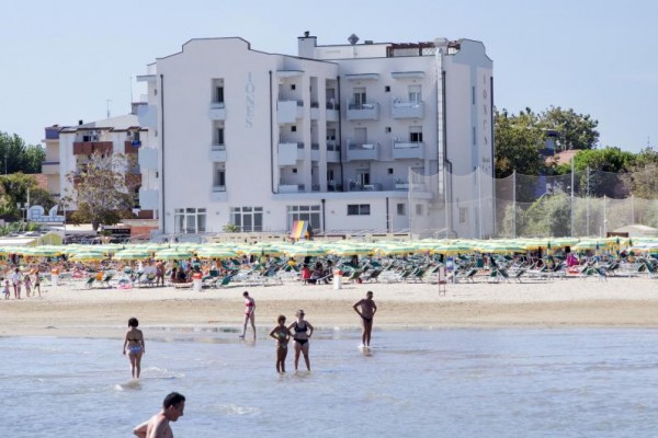 Pláž s lidmi a hotel v pozadí.