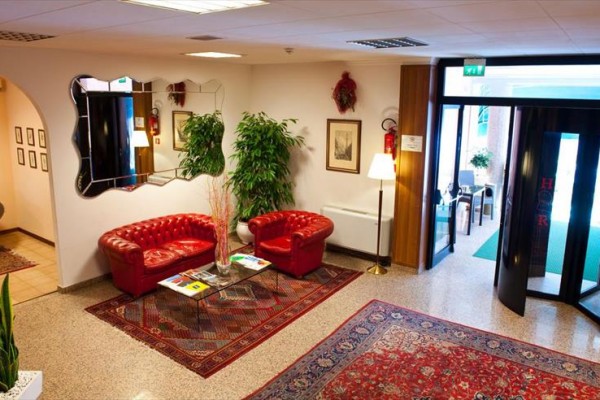 Lounge s červenými koženými pohovkami a orientálními koberci vedle prosklených dveří.