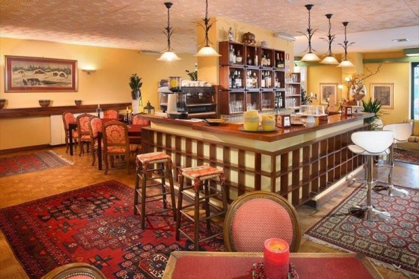 Uvnitř restaurace s dřevěným barem a červenými koberci.