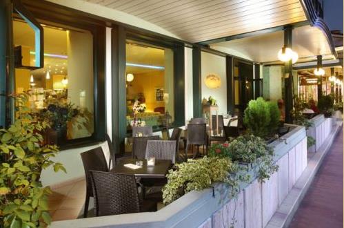 Venkovní posezení restaurace s proutěnými židlemi a rostlinami.