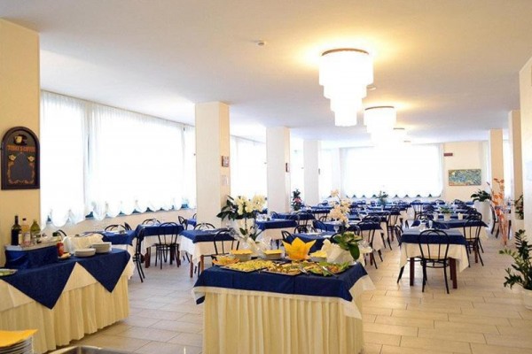 Světlá restaurace s modrobílými ubrusy a stolky připravenými pro hosty.