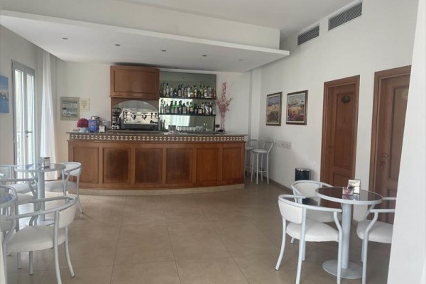 Malý bar s dřevěným pultem obklopený několika stolky a židlemi.