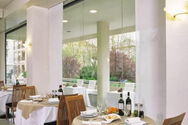 Luxusní restaurace s prostřenými stoly a velkými okny s výhledem do zahrady.