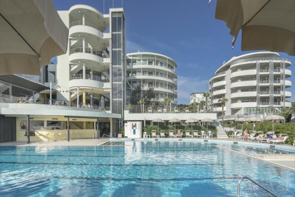 Moderní apartmány s bazénem lemovaným slunečníky.