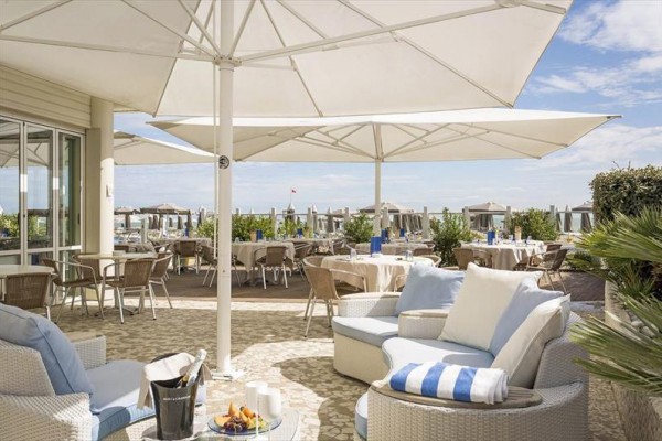 Venkovní terasa restaurace se slunečníky a pohodlnými křesly u pláže.