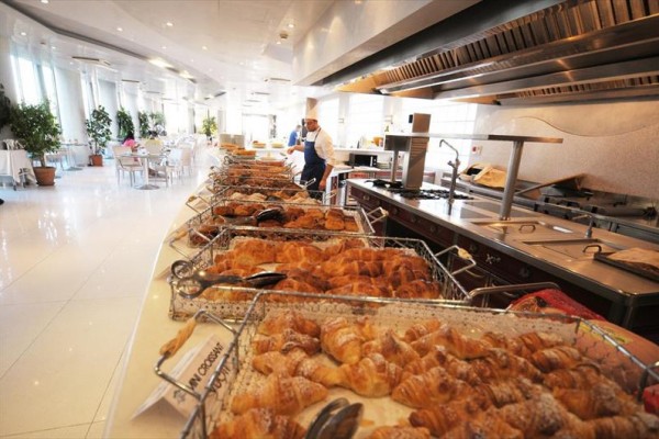 Šéfkuchař v restauraci s bufetem plným croissantů.