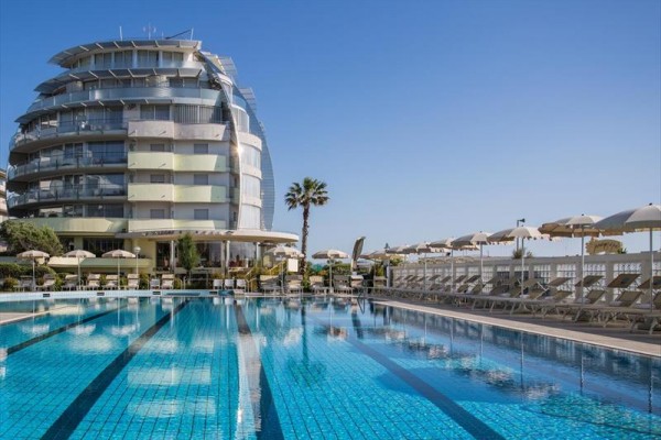 Moderní hotel s bazénem a lehátky pod slunečníky.