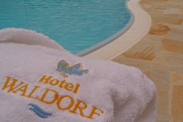 Bílý ručník s logem Hotel Waldorf u bazénu.  
