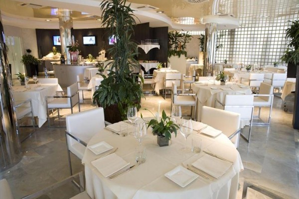 Elegantní restaurace s bílými ubrusy a moderními dekoracemi.