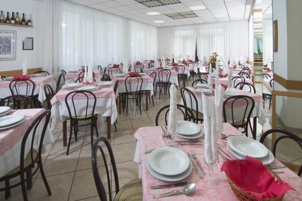 Restaurace s růžovými ubrusy a připravenými stolními sadami.