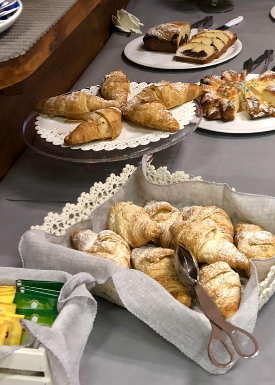 Různé pečivo jako croissanty a koláče vystavené na stole.