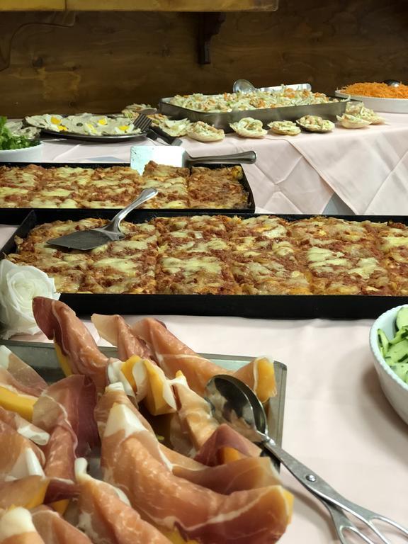 Stůl plný jídla včetně obložených mís se šunkou a pizzou.