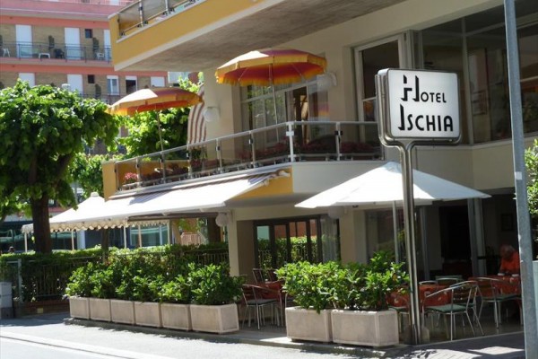 Hotel Ischia s venkovním posezením a barevnými slunečníky.