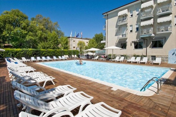 Venku je bazén s lehátky kolem něj u hotelu s několika patry.