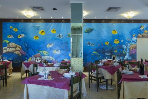 Restaurace s podmořskou nástěnnou malbou a prostřenými stoly.
