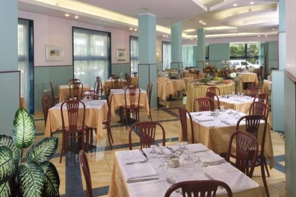 Prostorná restaurace s prostřenými stoly a dřevěnými židlemi.