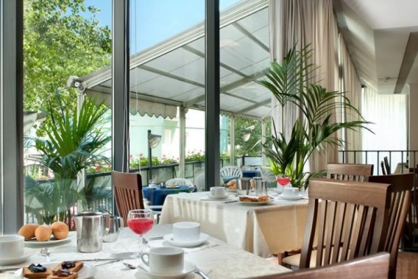 Restaurace s dřevěnými stoly a výhledem na venkovní terasu.