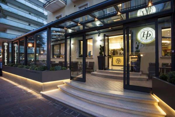 Vstup do hotelu s prosklenou verandou a osvětleným schodištěm.