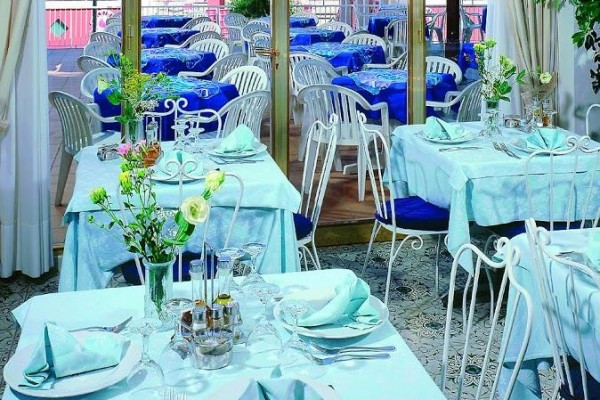 Elegantně prostřený interiér restaurace s výhledem na terasu a moře.