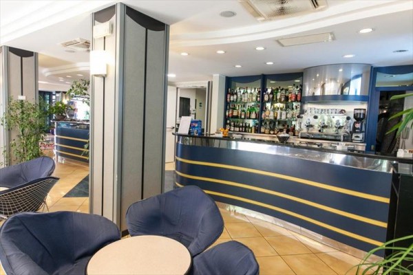 Moderní hotelový bar s modrými křesly a policemi s nápoji.  