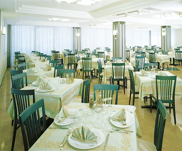 Restaurace s prostřenými stoly a zelenými židlemi.