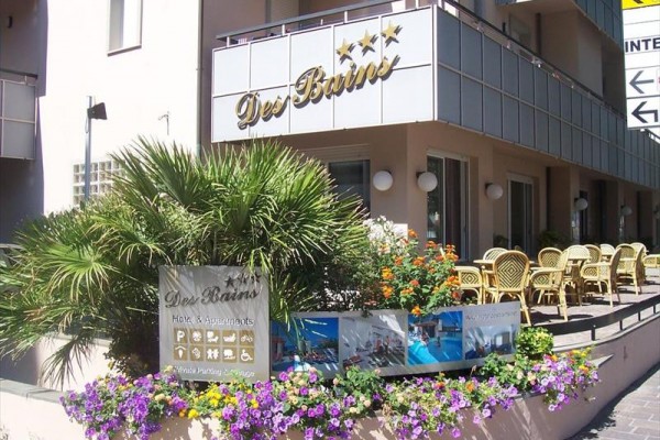 Vchod do hotelu Des Bains s venkovním posezením a květinovou výzdobou.