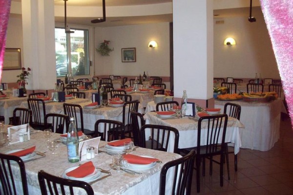 Restaurace s prostřenými stoly a černými židlemi.