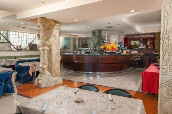 Interiér restaurace s prostřenými stoly a barem v pozadí.