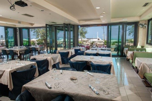 Restaurace s prostřenými stoly a výhledem na venkovní terasu.