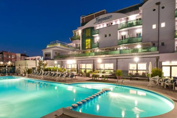 Hotel s osvětleným bazénem v noci.  